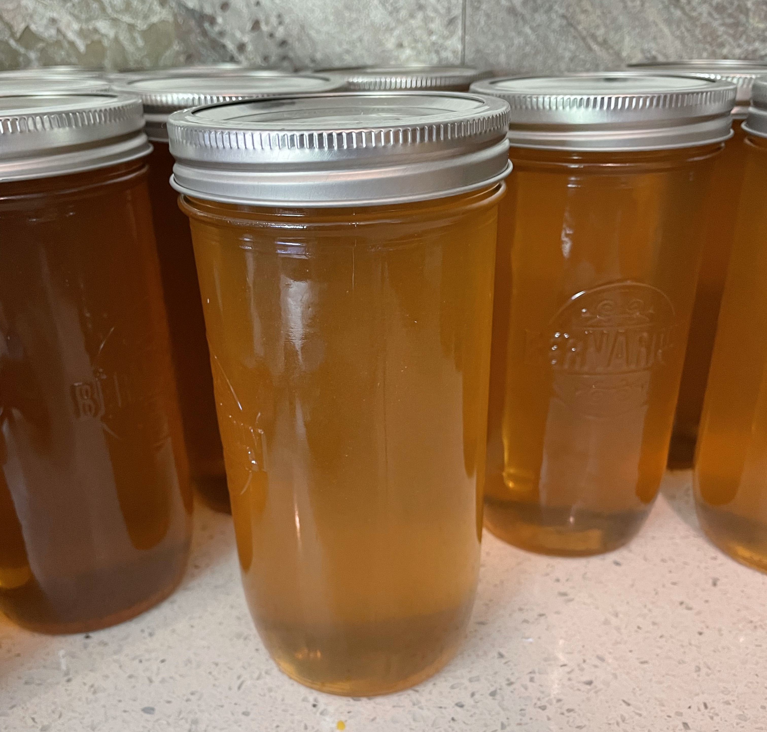 Several 750ml mason jars filled with golden Ella Park Honey